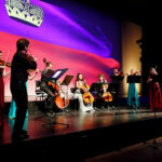 Musiker und Musikerinnen spielen vor Leinwand am Jubiläum 100 Jahre LGT 